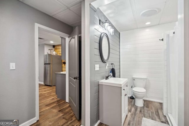 bathroom featuring toilet, vanity, baseboards, and wood finished floors