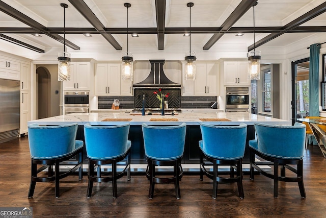 kitchen featuring custom range hood, dark wood-style floors, stainless steel appliances, arched walkways, and white cabinetry