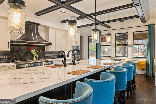 kitchen with custom exhaust hood, coffered ceiling, a wealth of natural light, and a sink