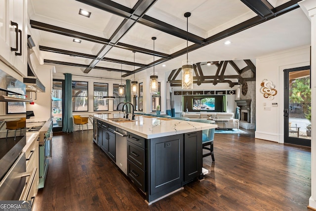 kitchen with a sink, a large fireplace, open floor plan, dark wood-style flooring, and dark cabinets