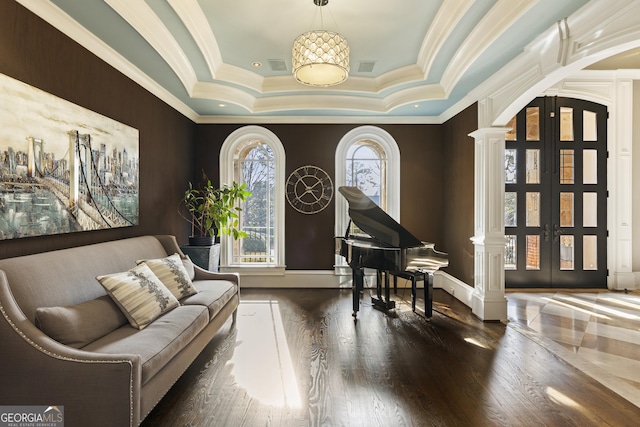 living area featuring arched walkways, plenty of natural light, a raised ceiling, and decorative columns