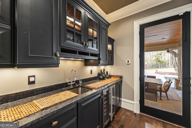 kitchen featuring a sink, dark stone counters, dark cabinetry, and crown molding