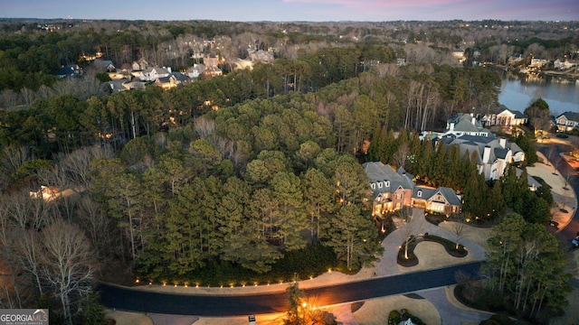 aerial view at dusk featuring a view of trees and a water view