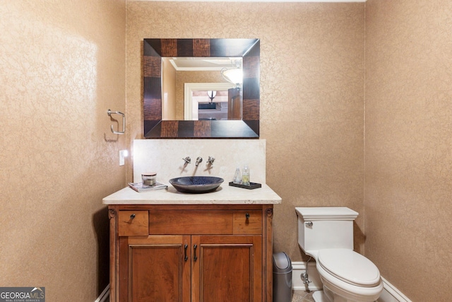 half bathroom featuring toilet, vanity, and baseboards