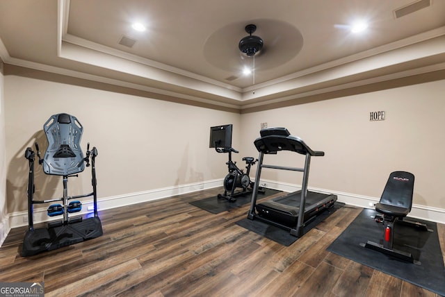 workout room featuring visible vents, crown molding, a tray ceiling, and wood finished floors