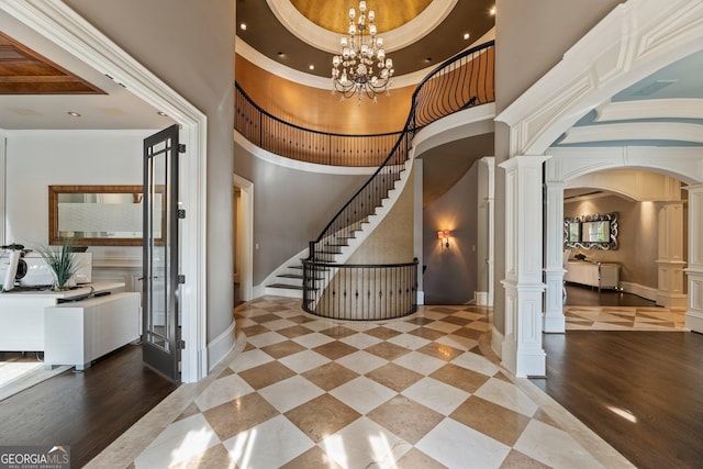 stairs featuring an inviting chandelier, a high ceiling, arched walkways, and ornate columns