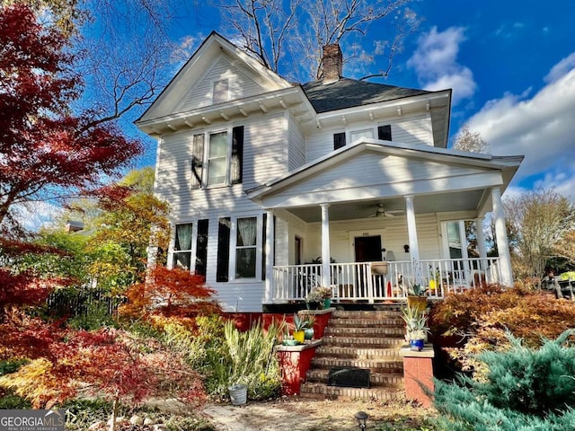 view of front of property with ceiling fan, a porch, a chimney, and stairway