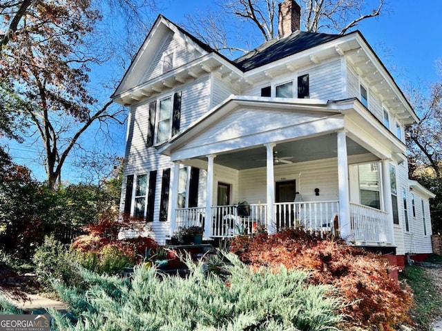 view of front facade with covered porch, a chimney, and a ceiling fan