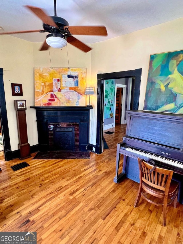 living room with baseboards, a fireplace with flush hearth, visible vents, and wood finished floors