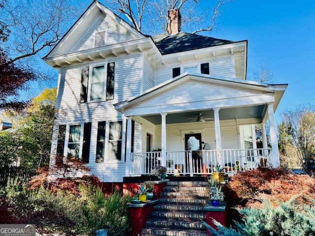 view of front of home with covered porch, a chimney, and stairs