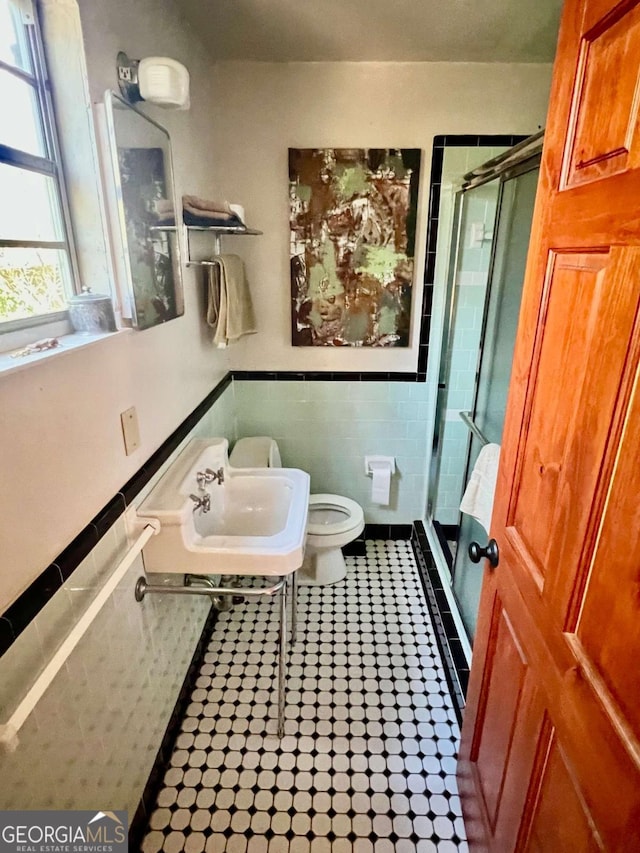 bathroom with toilet, tile patterned flooring, a shower stall, and tile walls