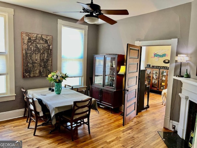 dining area with light wood finished floors, a fireplace, and a healthy amount of sunlight