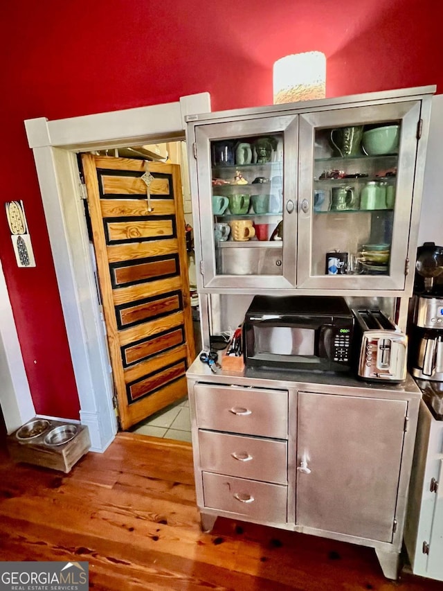 bar with black microwave and wood finished floors