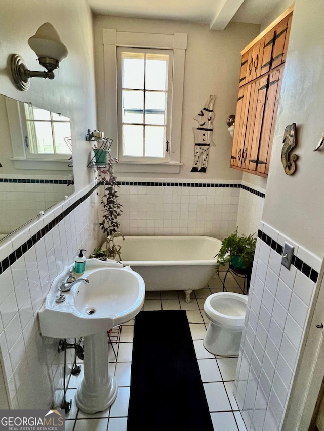 full bathroom featuring wainscoting, a soaking tub, tile patterned flooring, and toilet