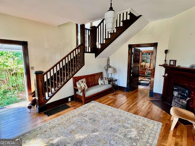 stairway featuring baseboards, a fireplace with flush hearth, visible vents, and wood finished floors