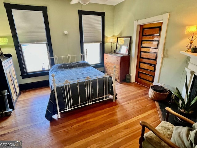 bedroom with a fireplace, wood finished floors, and baseboards