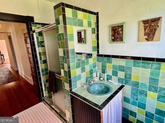 full bathroom featuring tile walls, a shower stall, vanity, and tile patterned floors