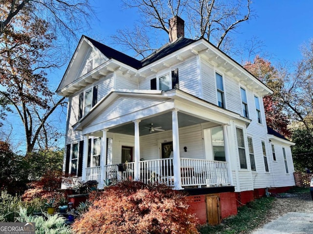 view of front facade with a chimney, a porch, and a ceiling fan