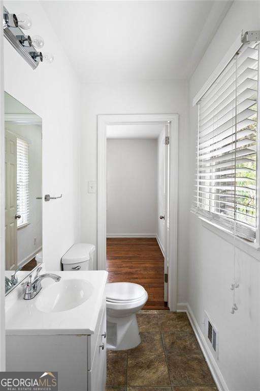 bathroom with toilet, baseboards, visible vents, and vanity