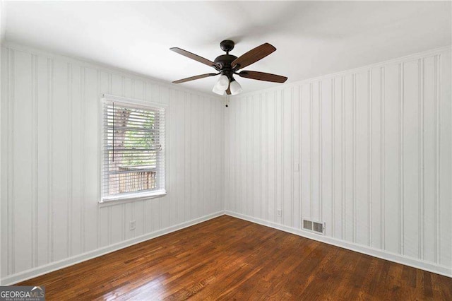 empty room featuring ceiling fan, dark wood-type flooring, visible vents, and baseboards