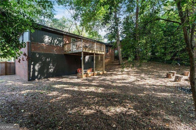 rear view of house with fence, a deck, and brick siding