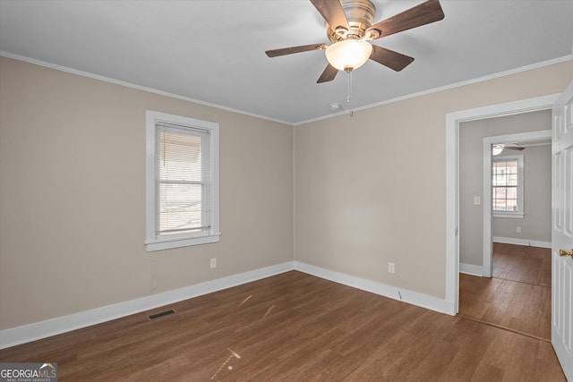 unfurnished room with dark wood-style floors, visible vents, and ornamental molding