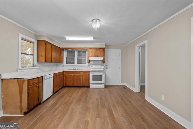 kitchen featuring brown cabinetry, white appliances, a sink, and under cabinet range hood