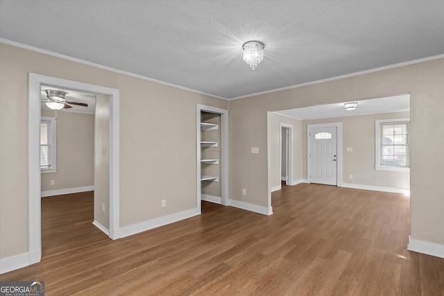 unfurnished living room featuring baseboards, ornamental molding, and wood finished floors