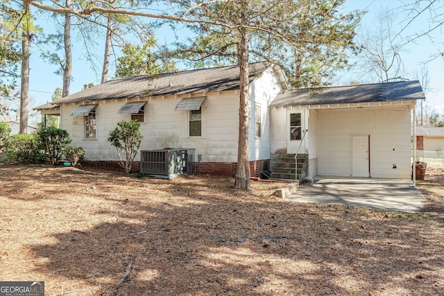 rear view of house with entry steps, a shingled roof, and central AC unit