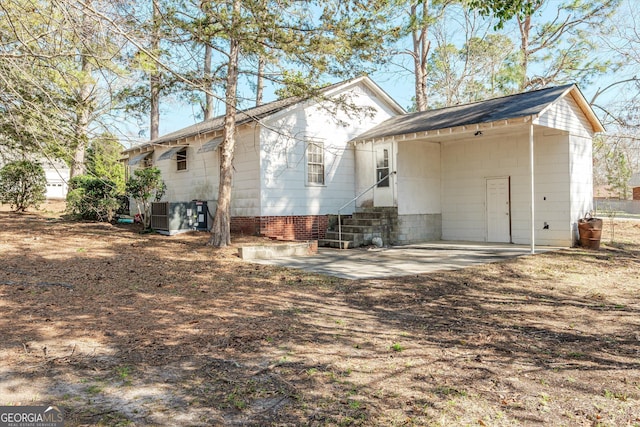 back of property with entry steps, driveway, an attached carport, and central air condition unit