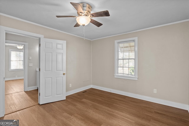 unfurnished bedroom with ornamental molding, ceiling fan, baseboards, and wood finished floors