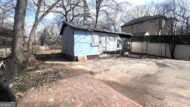 rear view of property featuring an outbuilding, fence, and a patio