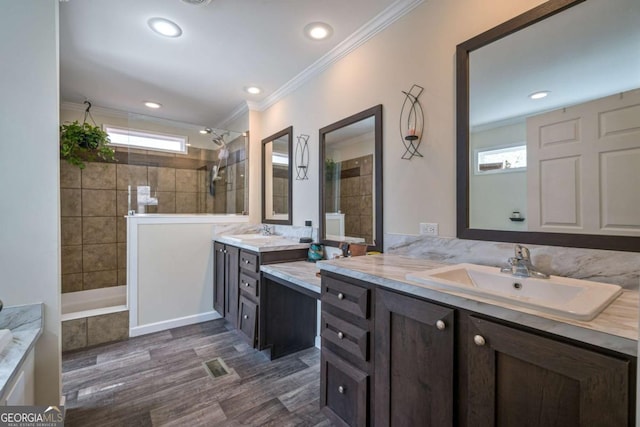 full bath featuring ornamental molding, a sink, and tiled shower