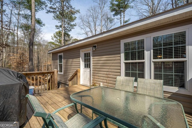 wooden deck with outdoor dining space and area for grilling