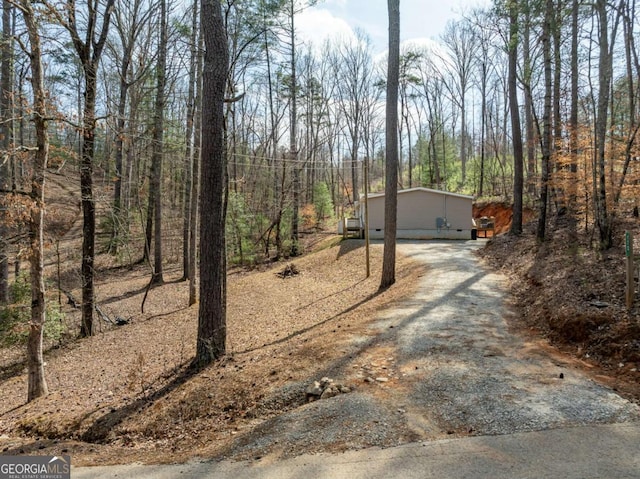 exterior space featuring gravel driveway and a wooded view