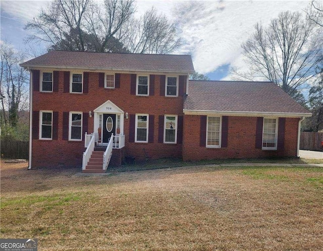 colonial-style house with brick siding, crawl space, a front yard, and fence