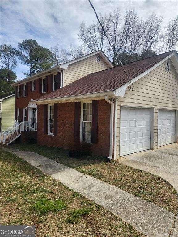 view of home's exterior with driveway, roof with shingles, a garage, and brick siding