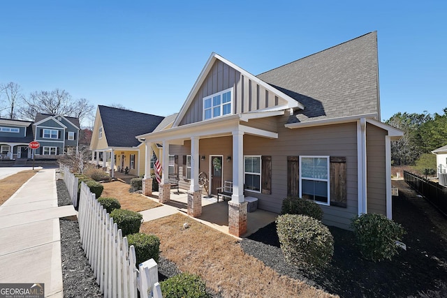 view of front of home featuring covered porch, fence private yard, board and batten siding, and a shingled roof