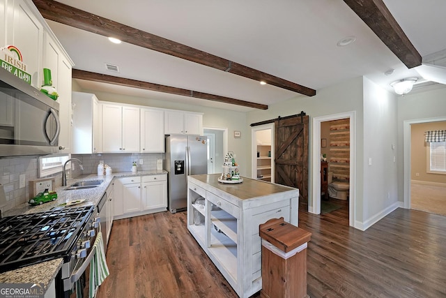 kitchen with visible vents, a sink, stainless steel appliances, a barn door, and a center island