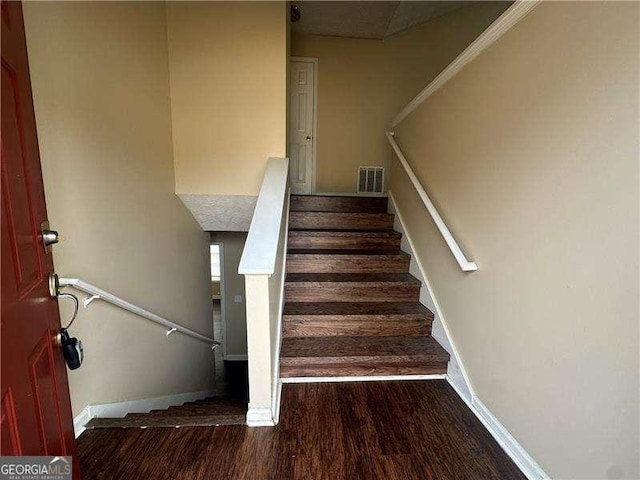 stairs with visible vents, baseboards, and wood finished floors