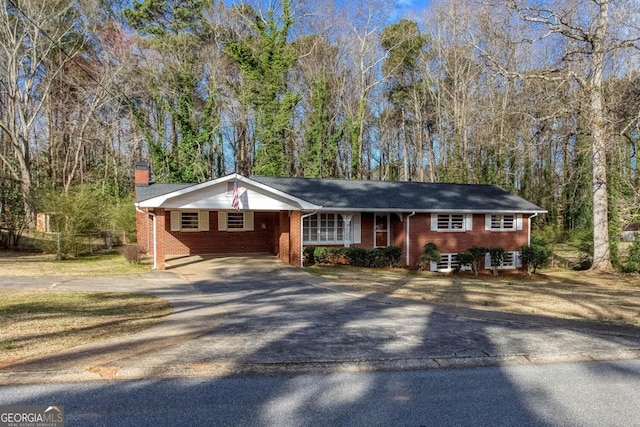 single story home featuring brick siding, driveway, and a chimney