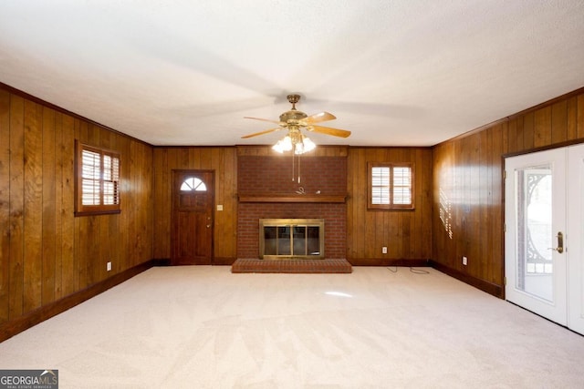 unfurnished living room with wood walls, ceiling fan, plenty of natural light, and baseboards