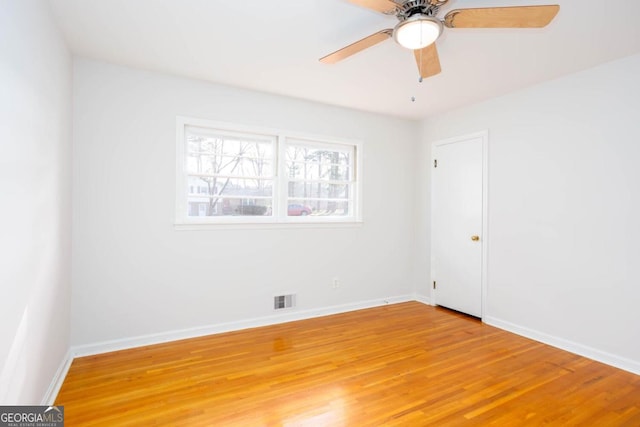 empty room with visible vents, light wood-style flooring, a ceiling fan, and baseboards