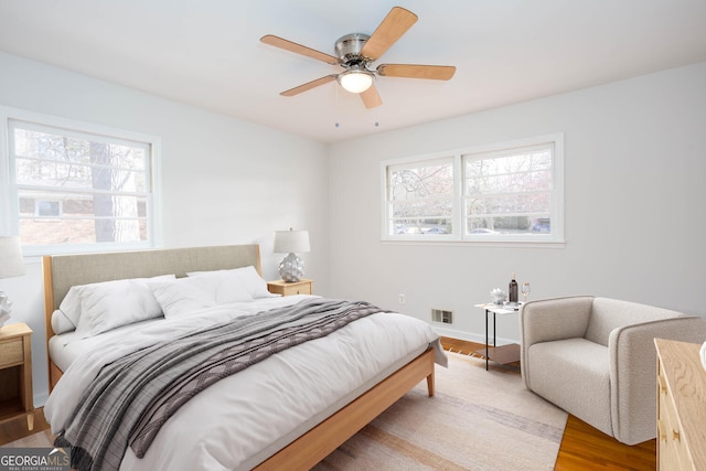 bedroom featuring light wood-style floors, a ceiling fan, and visible vents