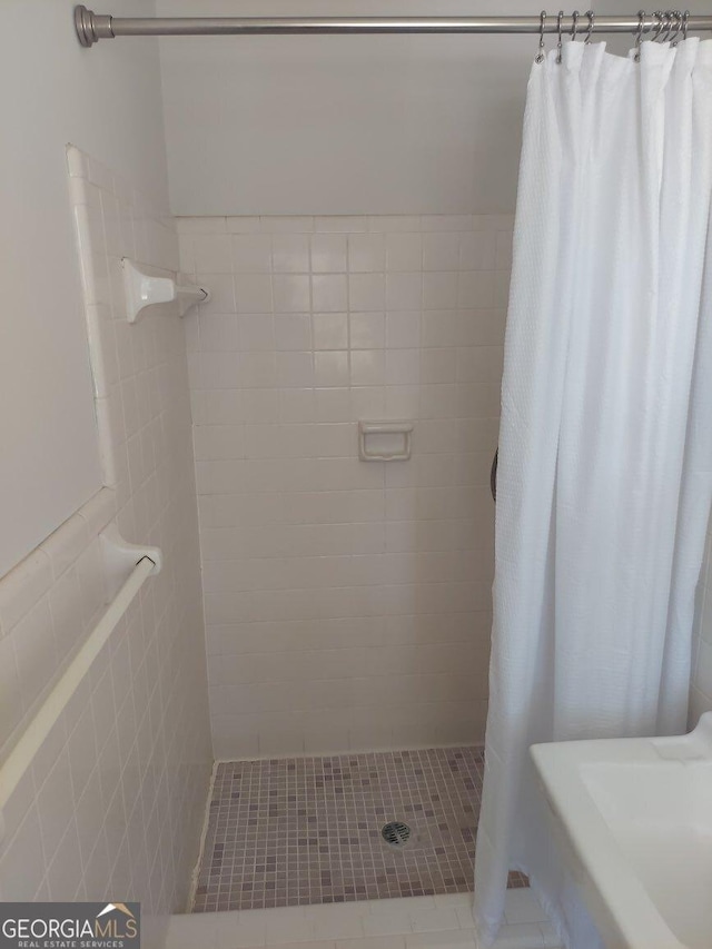 bathroom featuring tile patterned floors, tiled shower, and tile walls