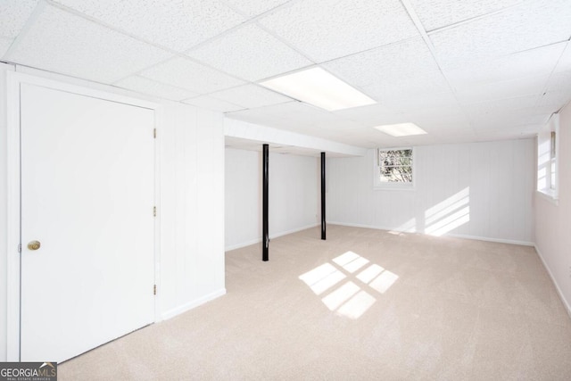 basement with a paneled ceiling, carpet flooring, and a wealth of natural light