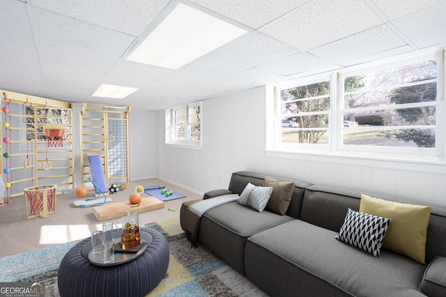 carpeted living room featuring a paneled ceiling and baseboards