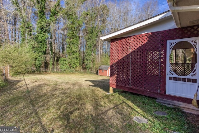view of yard featuring an outdoor structure, fence, and a storage unit