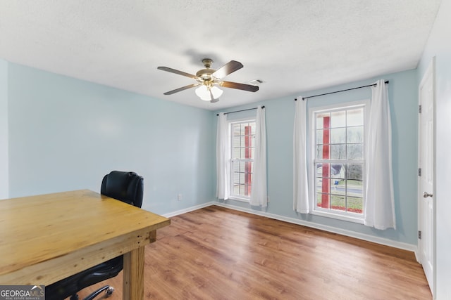 home office featuring visible vents, baseboards, a ceiling fan, light wood-style flooring, and a textured ceiling