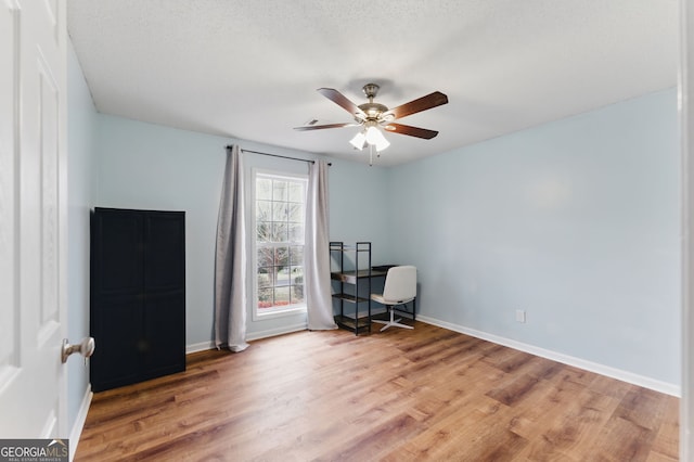 office area with a ceiling fan, a textured ceiling, baseboards, and wood finished floors